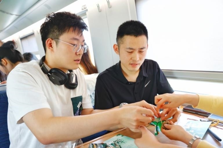 G232次旅客親手制作端午荷包和五彩繩。王磊攝